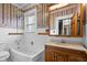 Classic bathroom featuring white tiled walls, wood vanity and vibrant floral wallpaper accents at 122 S Green St, Brownsburg, IN 46112