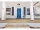 Close-up of a front porch featuring a bright blue door, white columns, and a porch swing at 122 S Green St, Brownsburg, IN 46112