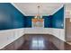 Dining room with wainscoting, bold blue walls, hardwood floors, and a decorative chandelier at 12404 Doe Ln, Indianapolis, IN 46236