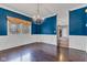 Dining room with wainscoting, bold blue walls, hardwood floors, and a decorative chandelier at 12404 Doe Ln, Indianapolis, IN 46236