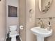 Charming half bathroom featuring a pedestal sink, toilet, decorative mirror and wall mounted cabinet at 12404 Doe Ln, Indianapolis, IN 46236