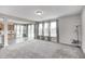 Large carpeted living room with gray walls and lots of natural light; kitchen cabinets are visible in the background at 13115 N Departure W Blvd, Camby, IN 46113