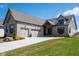 Beautiful gray brick home featuring an attached two-car garage and a well-manicured lawn and driveway at 16392 Grand Cypress Dr, Noblesville, IN 46060