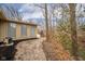 Back exterior of home with brick fireplace, gravel, and surrounded by trees at 208 Northshore Blvd, Anderson, IN 46011