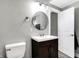 Cozy bathroom featuring a dark wood vanity, toilet, round mirror, and modern lighting at 3145 N New Jersey St, Indianapolis, IN 46205