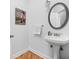 A well-lit half bathroom with a white pedestal sink and a round mirror, complemented by modern artwork at 450 E Ohio St # Apt 118, Indianapolis, IN 46204