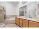 Bright bathroom featuring double sinks, a large mirror, and a tiled shower and tub combo at 450 E Ohio St # Apt 118, Indianapolis, IN 46204