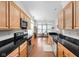 Open kitchen with wood cabinets, black counters, stainless appliances, and leads into the dining area at 450 E Ohio St # Apt 118, Indianapolis, IN 46204