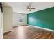 Bedroom with green accent wall, hardwood floors, window, and ceiling fan at 5546 W Vistaview Trl, McCordsville, IN 46055
