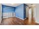 Bedroom with hardwood floors, blue accent wall, and white built-in shelving at 5546 W Vistaview Trl, McCordsville, IN 46055