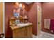 The bathroom features a decorative vanity, round mirror, unique lighting, and warm, dark-red paint at 5895 W 265 N, Columbus, IN 47201