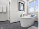 Bright bathroom with a freestanding tub, herringbone floor, and large window at 5895 W 265 N, Columbus, IN 47201