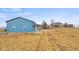 View of the exterior of the blue barn style garage on a large open lot with a house in the background at 5895 W 265 N, Columbus, IN 47201