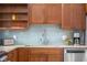 Kitchen featuring wooden cabinetry, granite countertops, stainless steel appliances, and light blue backsplash at 5895 W 265 N, Columbus, IN 47201