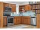 Kitchen featuring stainless appliances, light blue backsplash, and wood cabinetry with a spiral staircase alongside at 5895 W 265 N, Columbus, IN 47201