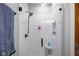 Shower with white tile, glass door, showerhead, and small corner shelves for bath products at 5895 W 265 N, Columbus, IN 47201