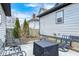 View of gray home with a black firepit, small stone patio, and iron chairs in the fenced-in backyard at 602 E Beecher St, Indianapolis, IN 46203