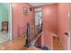 Hallway with wooden floor, pink walls, and dark banister with safety gate at 6428 Bluff Crest Ct, Indianapolis, IN 46217