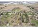 An aerial view displays an expansive field adjacent to a cluster of homes and industrial warehouses at 7089 W 150 N, Greenfield, IN 46140