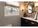 Cozy bathroom with dark vanity, brick accent wall, oval mirror, and stylish lighting fixtures at 7089 W 150 N, Greenfield, IN 46140