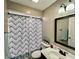 Well-lit bathroom with a patterned shower curtain, white vanity, and stylish mirror at 1820 N Dequincy St, Indianapolis, IN 46218