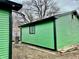 View of green home exterior highlighting siding, black trim, and backyard setting at 1820 N Dequincy St, Indianapolis, IN 46218