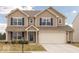 Charming two-story home with neutral siding, dark blue shutters, an attached two-car garage, and a well-manicured lawn at 5021 Greenside Dr, Indianapolis, IN 46235