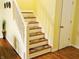 Carpeted staircase with a white banister, natural light, and hardwood flooring at the base, leading to the upper level at 5021 Greenside Dr, Indianapolis, IN 46235