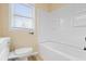 A white shower-tub combo is adjacent to the toilet, and natural light streams in through the window at 5441 E 34Th St, Indianapolis, IN 46218