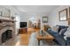 Open living room featuring hardwood floors, brick fireplace, and seamless flow to dining area at 5444 Carrollton Ave, Indianapolis, IN 46220