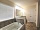Bathroom featuring a soaking tub with tile surround and a single sink vanity at 7027 Pinnacle Dr, Columbus, IN 47201