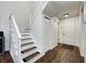 Hallway with a white staircase, wood floors, and a coat closet near the front door at 7459 Quincy Ct, Indianapolis, IN 46254