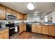 Eat-in kitchen with wood cabinets, stainless steel appliances, and a view of the dining area at 7459 Quincy Ct, Indianapolis, IN 46254