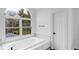 Bathroom featuring a soaking tub below a window offering a view of the yard and nearby trees at 12878 Mayfair Ln, Carmel, IN 46032