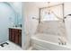 A bathroom with a large tub and a sink with a dark wood cabinet and a window with white curtains at 14402 Wolverton Way, Fishers, IN 46037