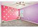 A playful bedroom featuring a polka dot pink wall, purple wall, ceiling fan, and window at 14402 Wolverton Way, Fishers, IN 46037