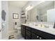 A well-lit bathroom featuring double vanity sinks with dark cabinetry, decorative shelves, a large mirror, and neutral-toned walls at 16613 Grappa Trl, Fishers, IN 46037
