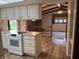 View of the kitchen with white cabinets, stove, and hardwood flooring that leads into the living room at 1701 Beech N Dr, Plainfield, IN 46168