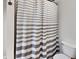 Bright bathroom with a gray and white striped shower curtain and a toilet at 205 S Market St, Thorntown, IN 46071