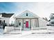 Charming home featuring a covered porch, pink front door, and white picket fence, all surrounded by a blanket of fresh snow at 205 S Market St, Thorntown, IN 46071