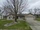 Beautiful single story tan brick home featuring a driveway, attached garage, and manicured lawn at 2129 Heather Rd, Anderson, IN 46012