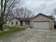 Charming brick house featuring a two-car garage, and a yard with a walkway and garden at 2129 Heather Rd, Anderson, IN 46012