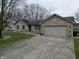 Charming brick house featuring a two-car garage, and a yard with a walkway and garden at 2129 Heather Rd, Anderson, IN 46012