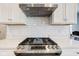 Close-up of gas range, stainless steel vent hood, white backsplash and countertop at 2627 Chalbury Dr, Plainfield, IN 46168