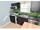 Well-lit kitchen featuring stainless steel appliances, subway tiles, and a sink with black countertops at 3533 N Grant Ave, Indianapolis, IN 46218