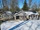 Charming gray home with stone accents, a welcoming wreath, and a snowy front yard at 717 Washington Ct, Anderson, IN 46011