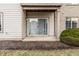 Private covered patio with sliding glass doors, offering a relaxing outdoor space with mulch and greenery at 9820 Legends Creek Dr # 103, Indianapolis, IN 46229
