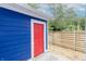 Exterior shot of vibrant blue siding, a red door, concrete, and a wooden fence at 1305 W 23Rd St, Indianapolis, IN 46208