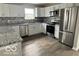 Modern kitchen featuring white cabinets, stainless steel appliances, and gray granite countertops at 1305 W 23Rd St, Indianapolis, IN 46208