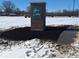 Community entrance sign in winter featuring stone base, set amidst a snow-covered landscape, welcoming residents at 1704 N Winthrop Rd, Muncie, IN 47304
